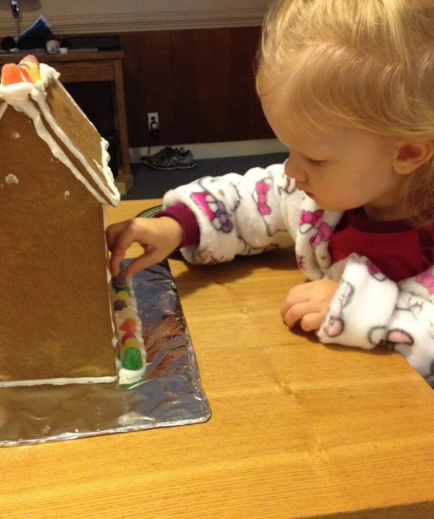 little girl decorating gingerbread house