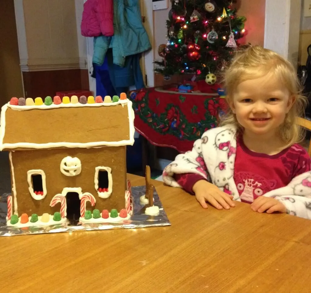 girl posing with gingerbread house