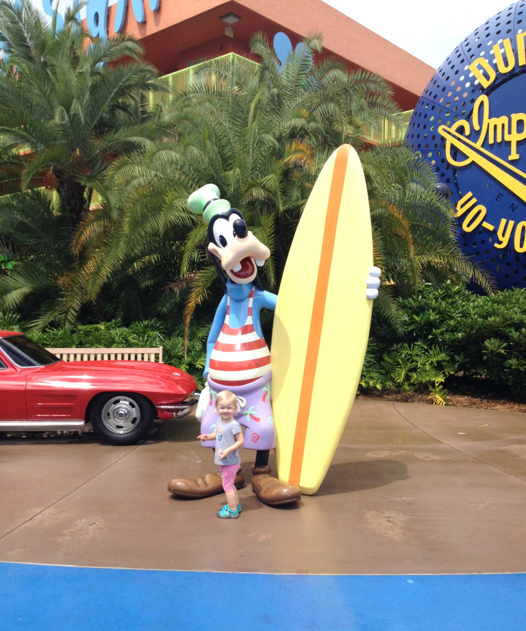 little girl posing with surfer goofy statue