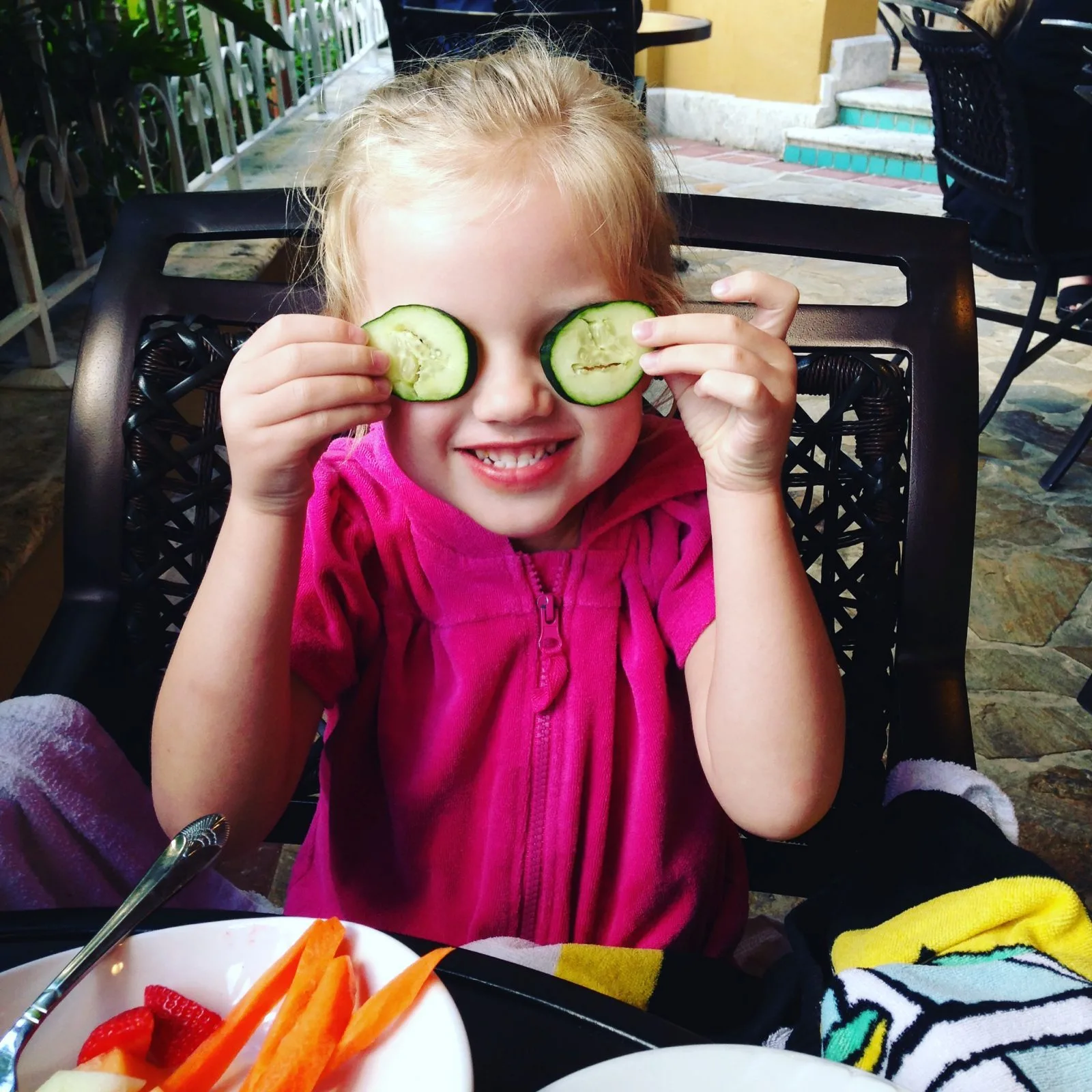 little girl playing with cucumbers over her eyes