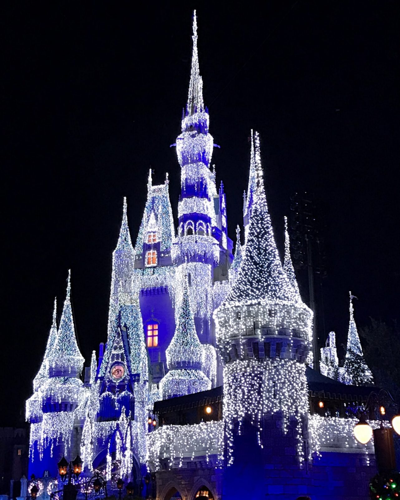 Cinderella's castle lit up at night with holiday lights