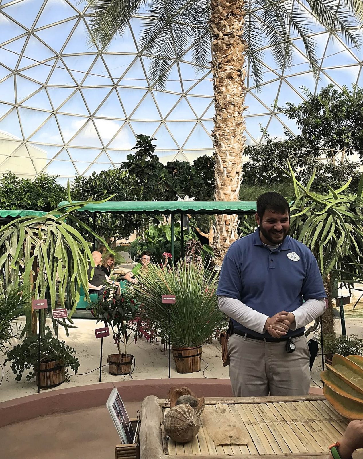 disney cast member giving a tour of the greenhouse with the living with the land ride in the background