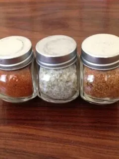 three small jars filled with spices, with lids