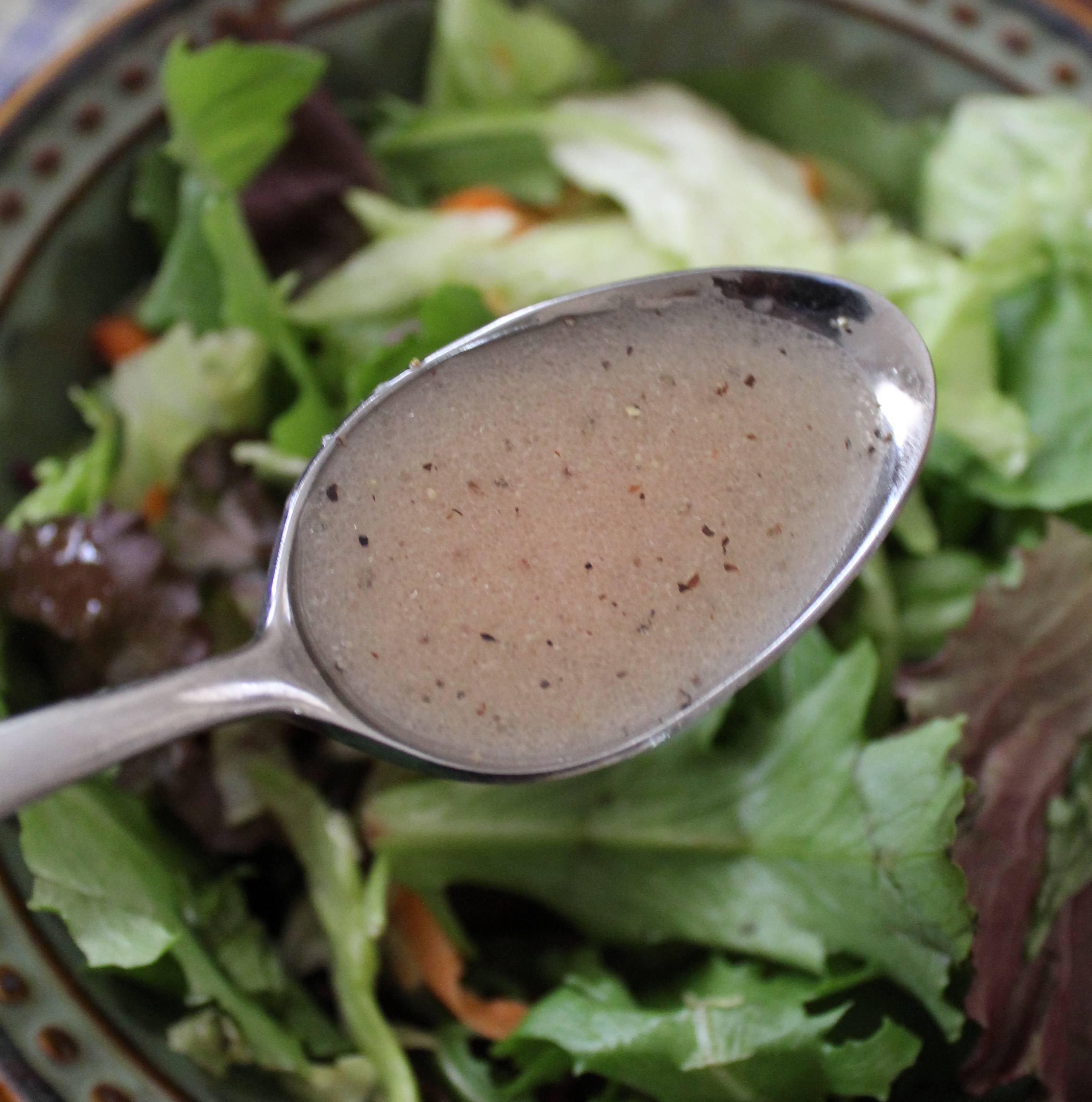 spoonful of homemade dressing over a salad
