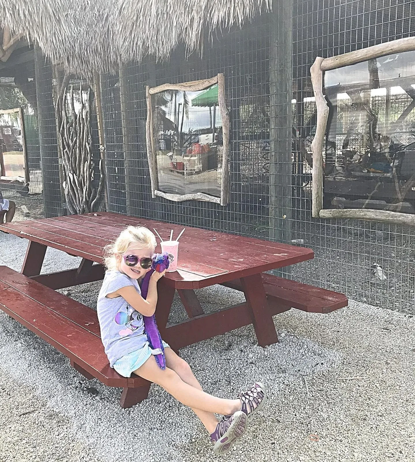 little girl enjoying a smoothie at a picnic table