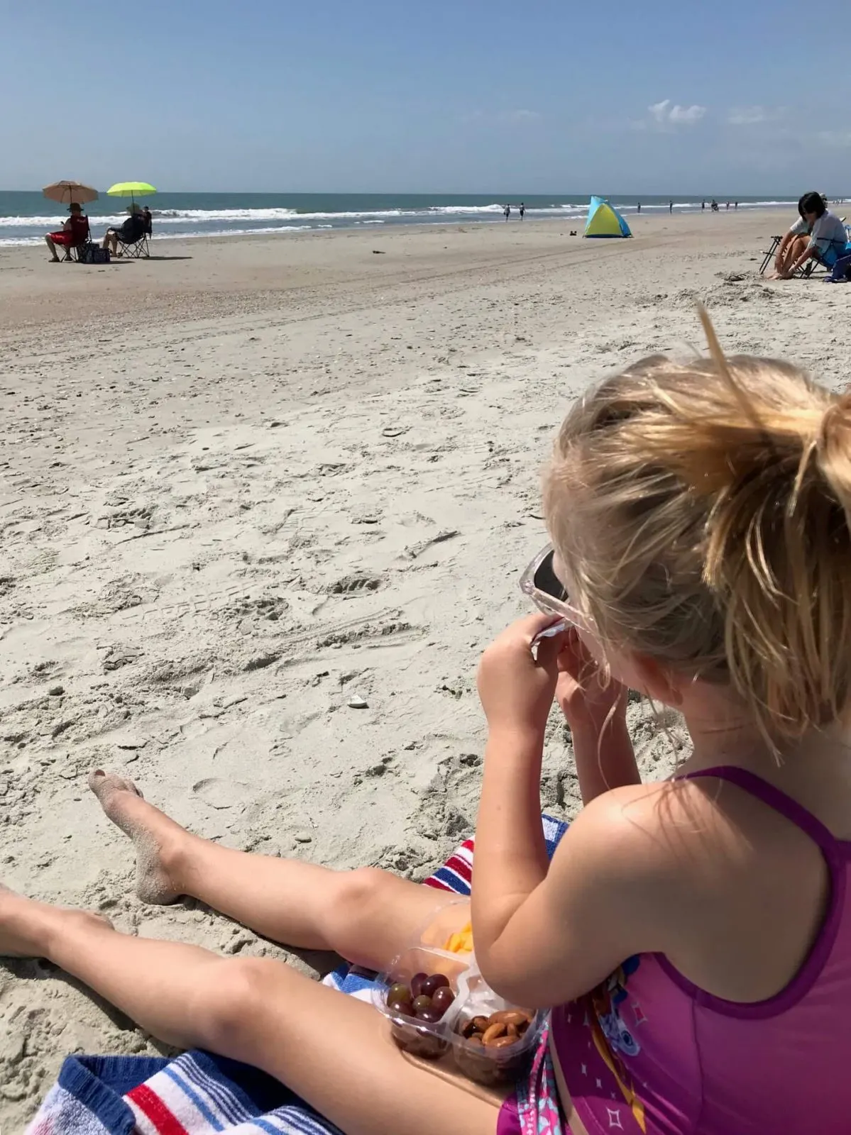 little girl enjoying a snack on the beach