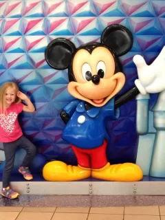 girl standing next to mickey statue