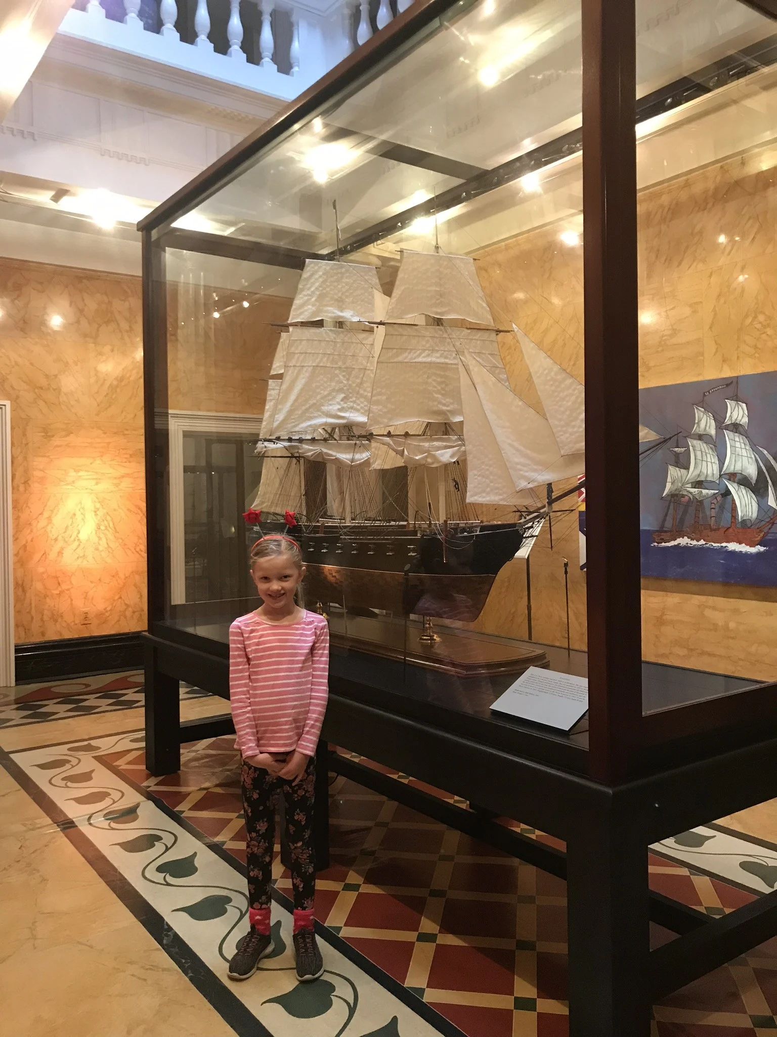 little girl in front of a display of ship replica