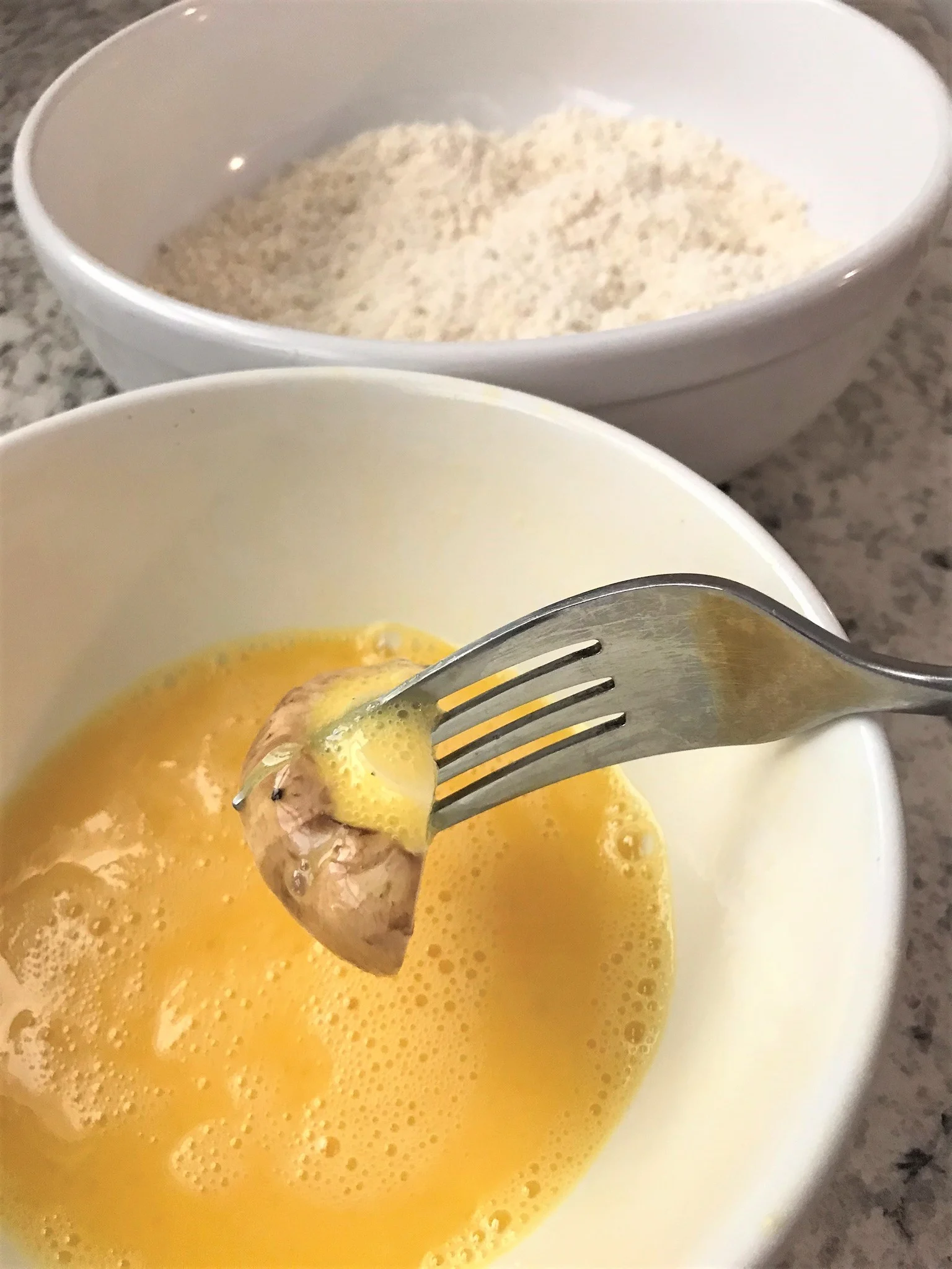 fork dipping mushroom in egg batter
