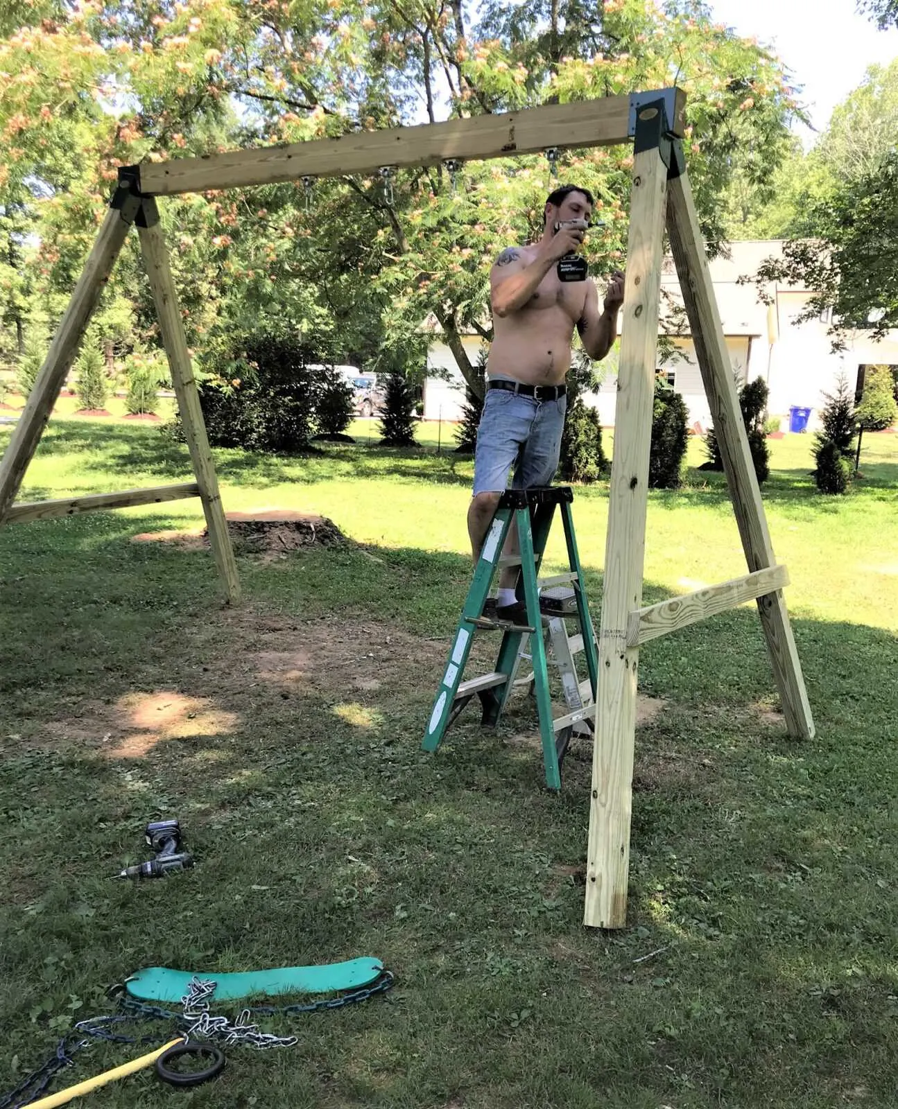 man with drill assembling swing set