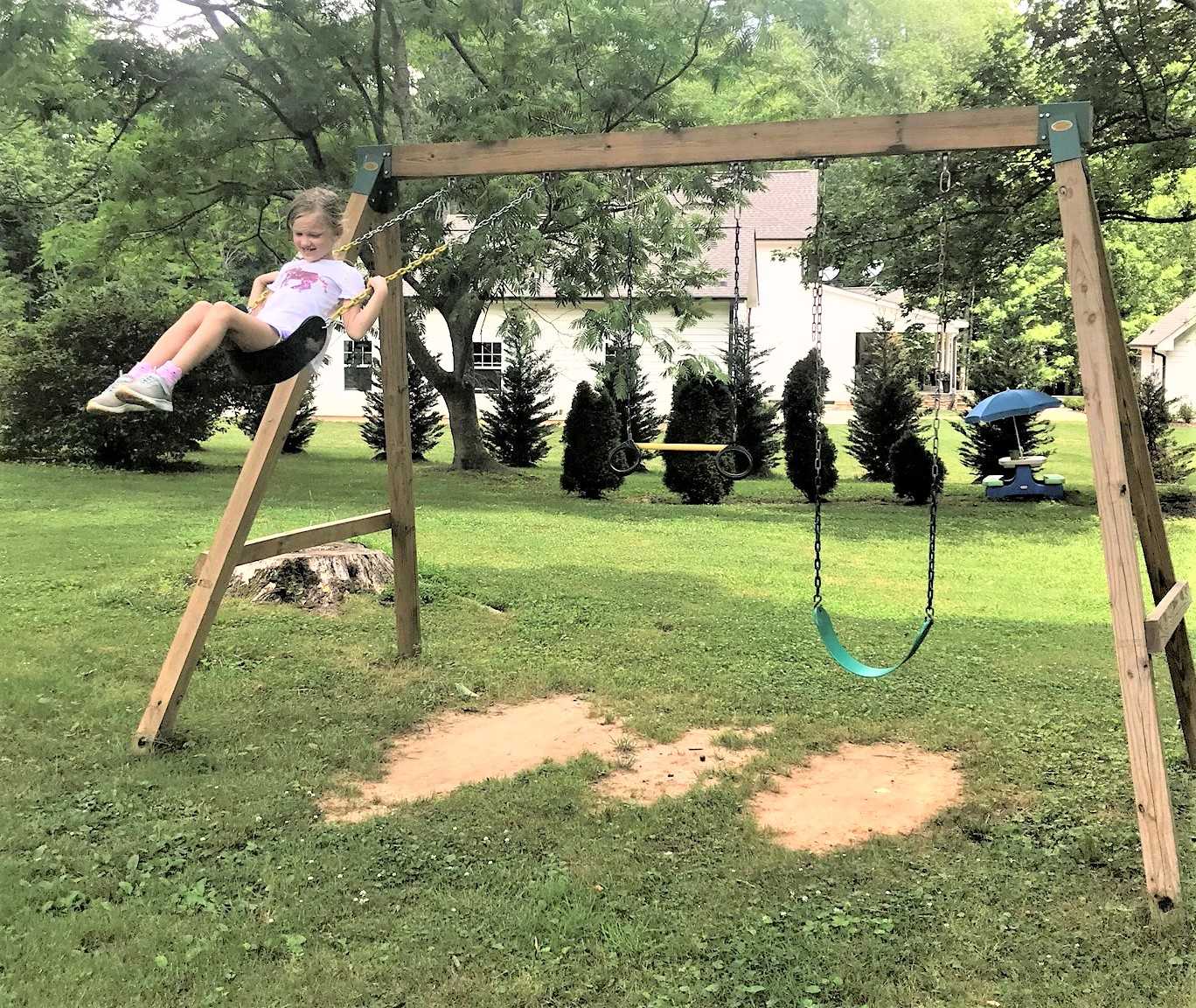 girl swinging on wooden swing set